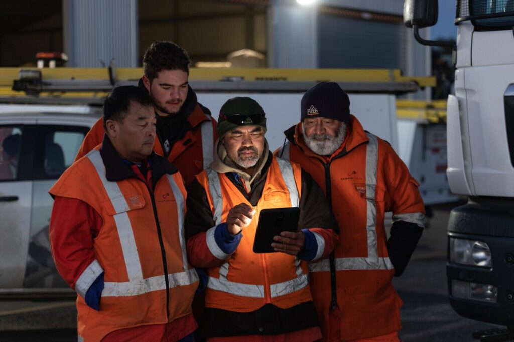 four staff members looking at a tablet in the field