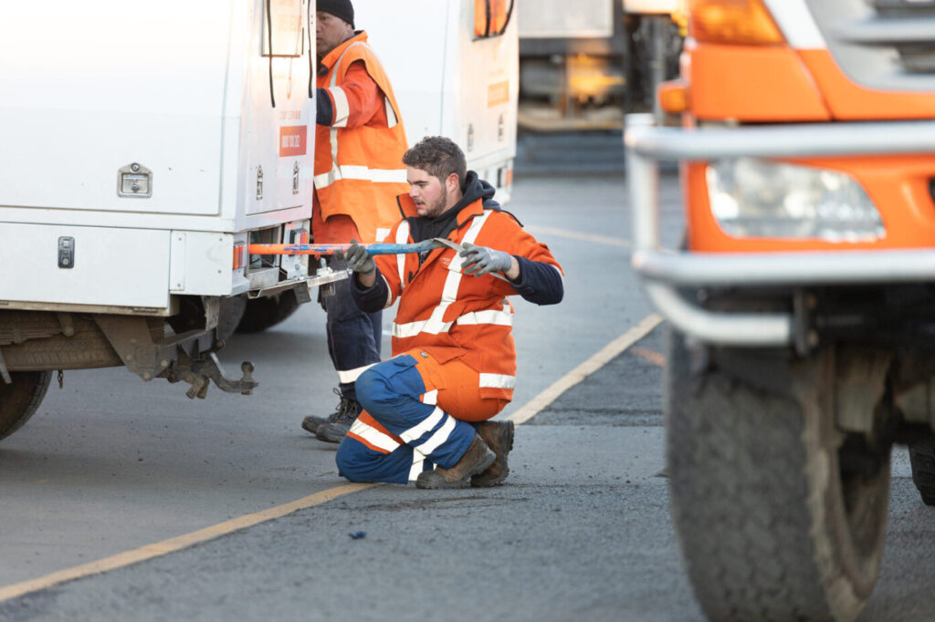 Crew putting shovel into the van kneeling down