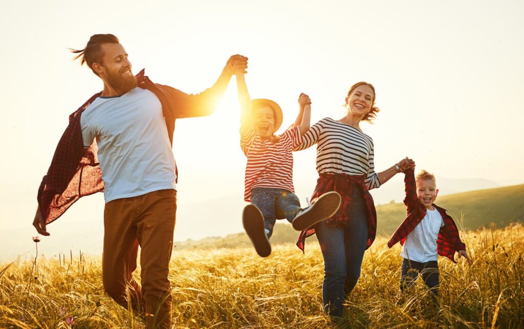 Family walking in a field smiling