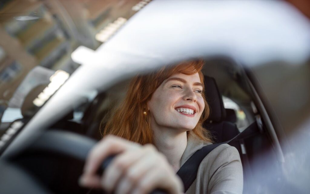 Female in her EV car smiling - image